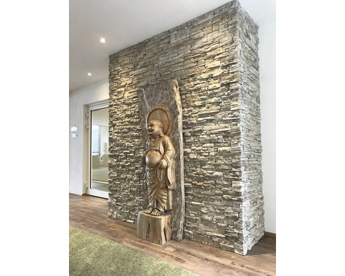 Interiér s obkladem stěn s kamenným vzhledem a sochou Buddhy