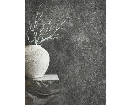Detail vázy s větvemi před tmavou, strukturovanou stěnou