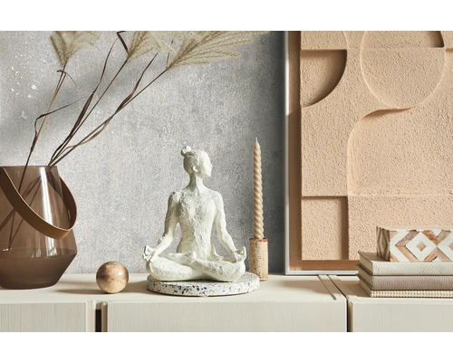 Dekorativní scéna s meditační figurkou, vázou, svíčkou a nástěnnou dekorací na komodě.