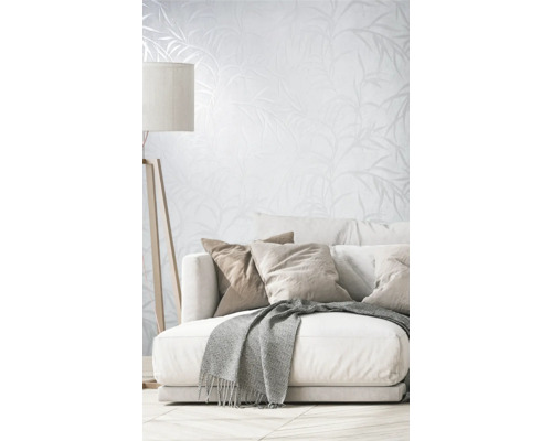 Obývací pokoj s pohovkou, polštáři, dekou, stojací lampou a tapetou s rostlinným vzorem