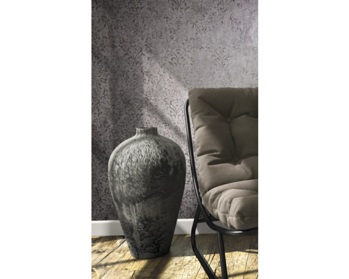 Dekorativní váza vedle židle před vzorovanou tapetou