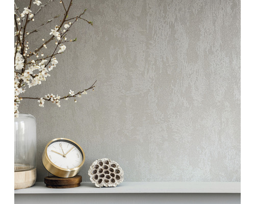 Detailní záběr nástěnné tapety s abstraktní texturou, kombinovaný s vázou, hodinami a lotosovým květem na polici