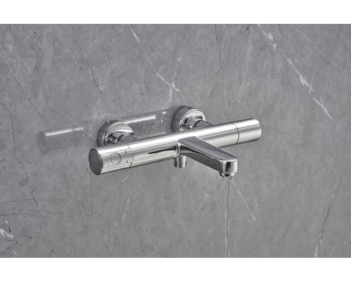 Nástěnná sprchová baterie před šedou stěnou s průtokem vody