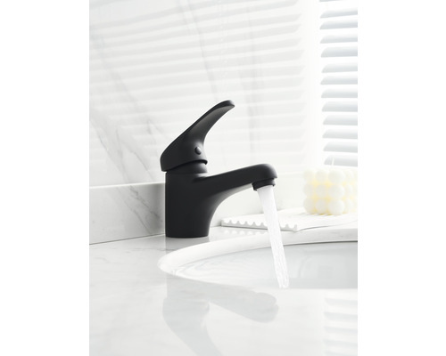 Černá vodovodní baterie s tekoucí vodou na umyvadle