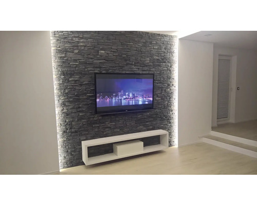 Moderní obývací pokoj s kamennou zdí, televizí a bílou skříňkou