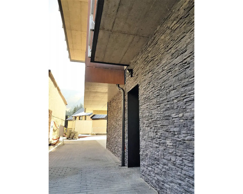 Exteriér budovy s kamennou zdí a dlážděným chodníkem