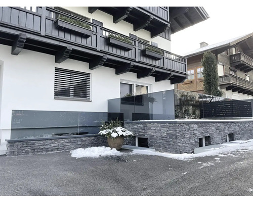 Fasáda domu se skleněným zábradlím a zdí z přírodního kamene