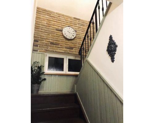 Schodiště s obložením stěn, cihlovou zdí, hodinami a dekorací.