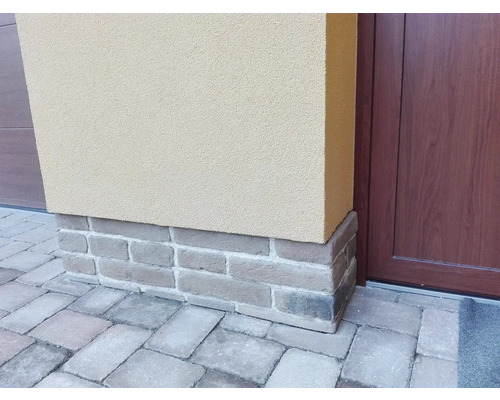 Exteriér budovy s cihlovým základem a dlažebními kostkami