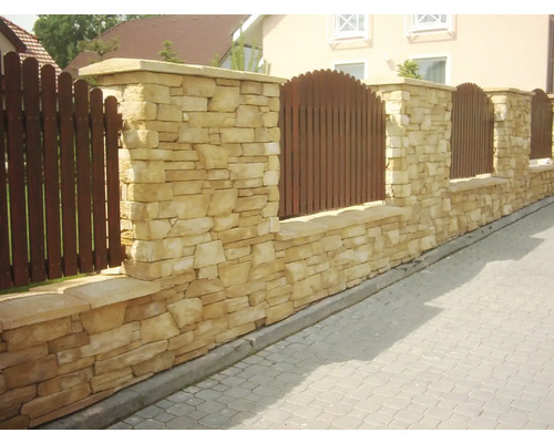 Venkovní pohled na kamennou zeď s dřevěným plotem