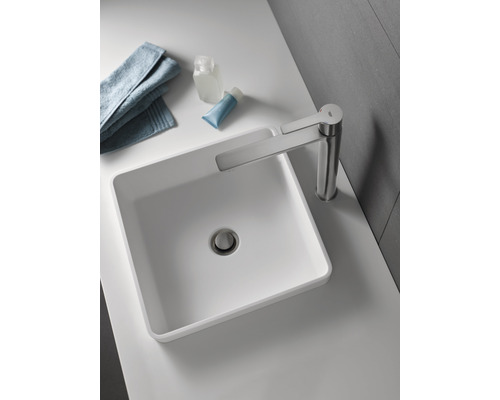 Na umyvadle je umyvadlová mísa s baterií, ručník a toaletní potřeby