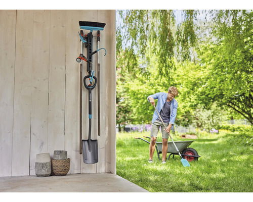 Zahradní scéna s držákem na nářadí, zahradním nářadím a osobou pracující na zahradě