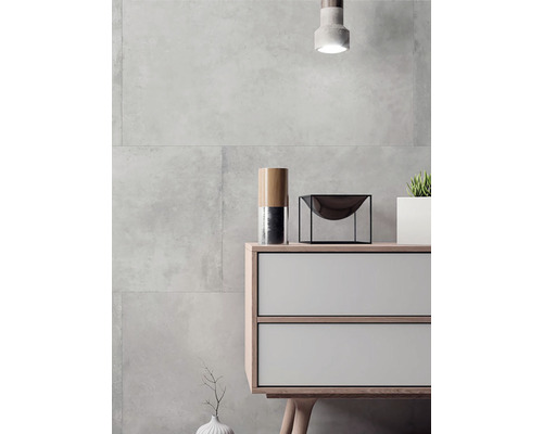 Moderní interiér s šedými obkladačkami, komodou a dekoracemi.