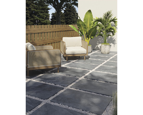 Terasa s šedými kamennými deskami, bílými okrasnými oblázky, dvěma křesly, dřevěným plotem a rostlinami