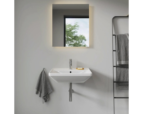 Moderní koupelna s umyvadlem, osvětleným zrcadlem a držákem na ručníky.