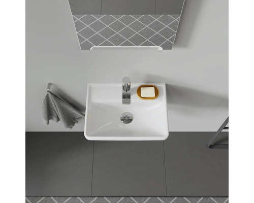 Pohled shora na koupelnu s umyvadlem, vodovodní baterií, zrcadlem, ručníkem a mýdlem