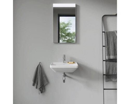 Pohled do koupelny s umyvadlem, zrcadlem a držákem na ručníky