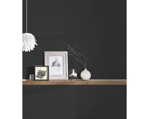 Dekorativní předměty na dřevěné polici před tmavou stěnou