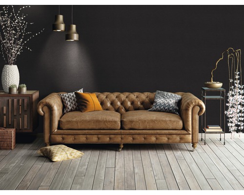 Obývací pokoj s hnědou koženou pohovkou ve stylu Chesterfield, dřevěnou podlahou a dekorativními prvky