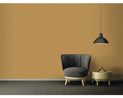 Obývací pokoj s křeslem, příručním stolkem a závěsnou lampou před jednobarevnou stěnou