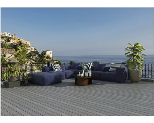 Pohled shora na šedou dřevěnou terasu s modrým zahradním nábytkem a výhledem na moře