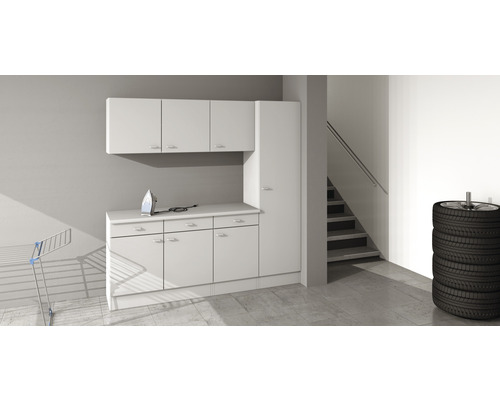 Světlá místnost s regálovým systémem, žehličkou, sušákem na prádlo a hromadou pneumatik