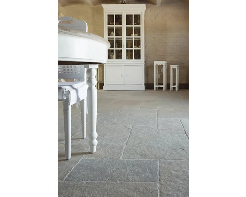 Interiér s kamennou dlažbou, bílým stolem a vitrínou