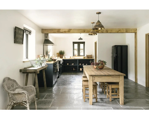 Světlá rustikální kuchyně s dřevěnými trámy, jídelním stolem, židlemi a kuchyňskou linkou