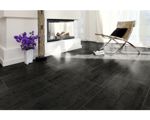 Obývací pokoj s tmavou dlažbou, krbem a křeslem.