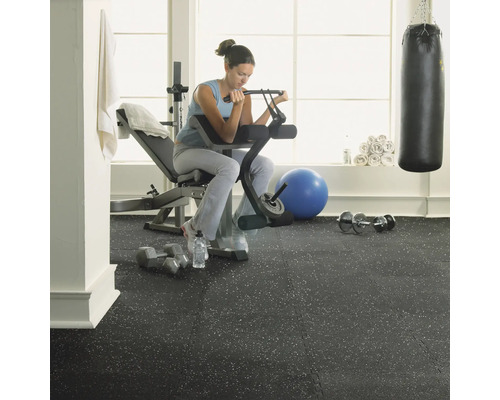 Posilovna s ženou cvičící na lavici s činkami na gumové podlaze