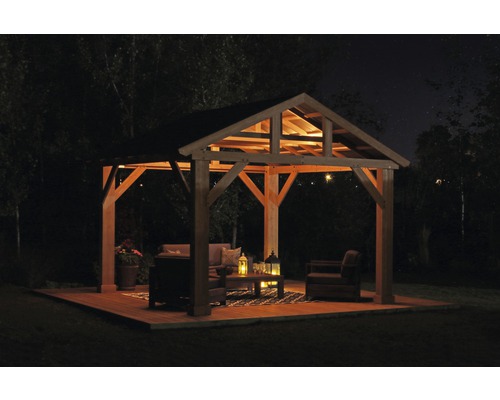 Osvětlený altán s zahradním nábytkem na dřevěné terase v noci.