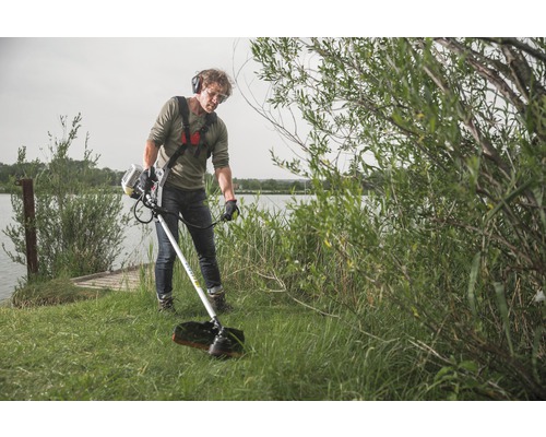 Muž obsluhuje vyžínač na břehu jezera s ochrannými brýlemi a sluchátky