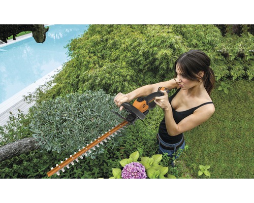 Žena stříhá živý plot nůžkami na živý plot na zahradě.