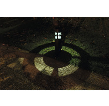 Zahradní lampa osvětluje trávník a kamenné desky ve tmě