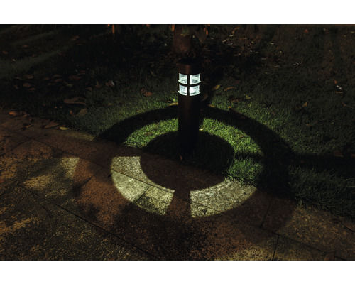 Zahradní lampa osvětluje trávník a kamenné desky ve tmě
