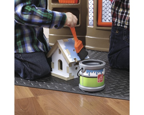 Dítě maluje domeček na hraní štětcem a kbelíkem barvy