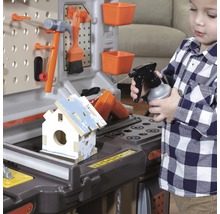 Dítě si hraje s pracovní lavicí a stříká vodu na ptačí budku