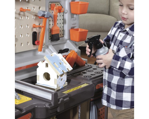 Dítě si hraje s pracovní lavicí a stříká vodu na ptačí budku