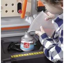 Dítě plní rozprašovač na pracovním stole vodou.