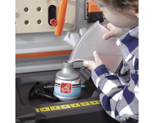 Dítě plní rozprašovač na pracovním stole vodou.