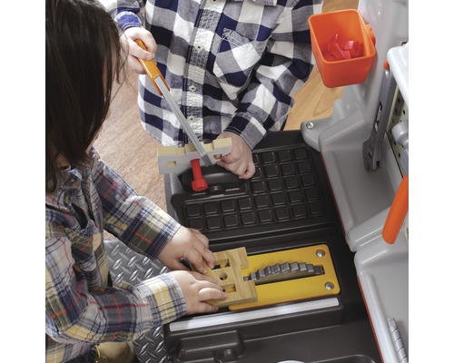 Dvě děti si hrají s pracovními stoly a nářadím.