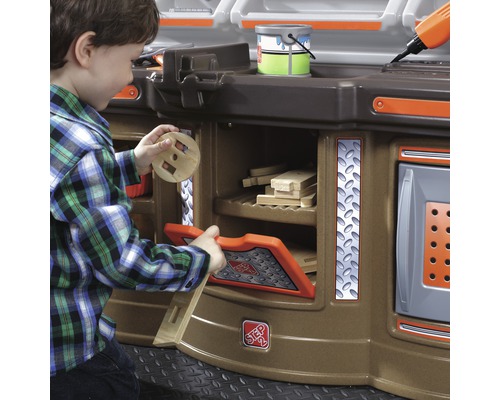 Chlapec si hraje s dětskou pracovní lavicí s úložným prostorem