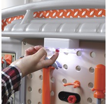 Detailní záběr na pracovní stůl s příslušenstvím a rukou ovládající spínač světla