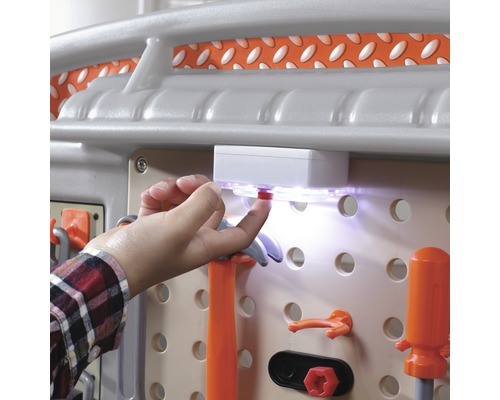 Detailní záběr na pracovní stůl s příslušenstvím a rukou ovládající spínač světla