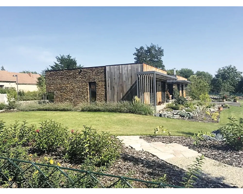 Moderní dům s kamennou fasádou a dřevěným obkladem, obklopený udržovanou zahradou.