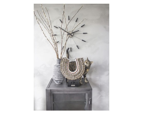 Dekorativní zátiší s hodinami, vázou s větvemi, sochou a kočkou na skříni