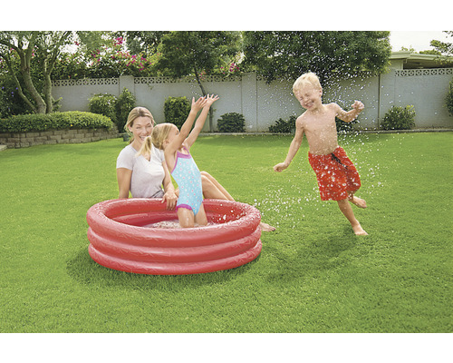 Matka a děti si hrají s brouzdalištěm na zahradě.