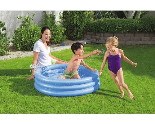 Scéna s dětmi hrajícími si v nafukovacím brouzdališti na zahradě