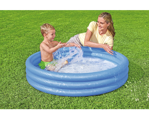 Dětský bazén s hrajícím si dítětem a dospělým na zahradě