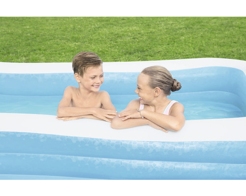 Dvě děti si hrají v nafukovacím bazénu na zahradě.